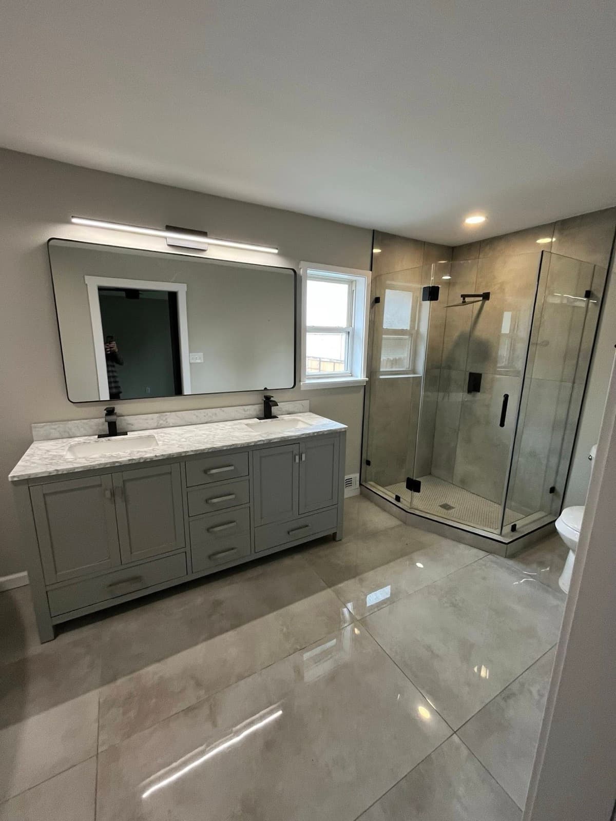 Bathroom with gray vanity, marble top, and glass shower enclosure